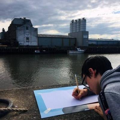 Young person sketching by the side of the river
