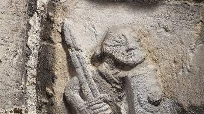 Stone carving of a person with a sword