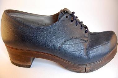 Dark grey leather lace-up shoe. The shoe has a wooden heel and a wooden sole which is hinged under the ball of the foot.